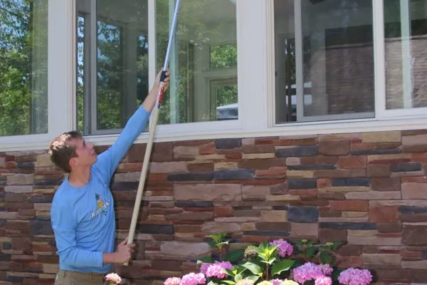 Technician removing spider webs from porch with dewebbing tool