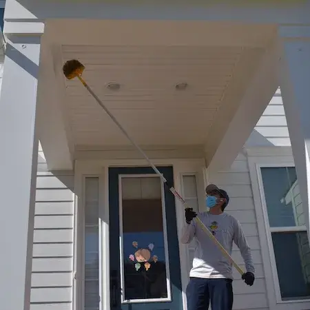 Pest control technician treating home exterior