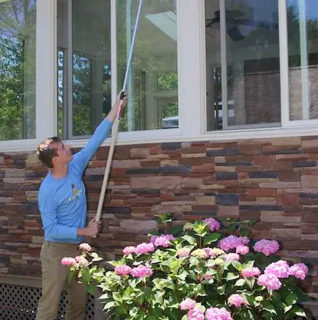Technician sweeping webs from exterior eaves