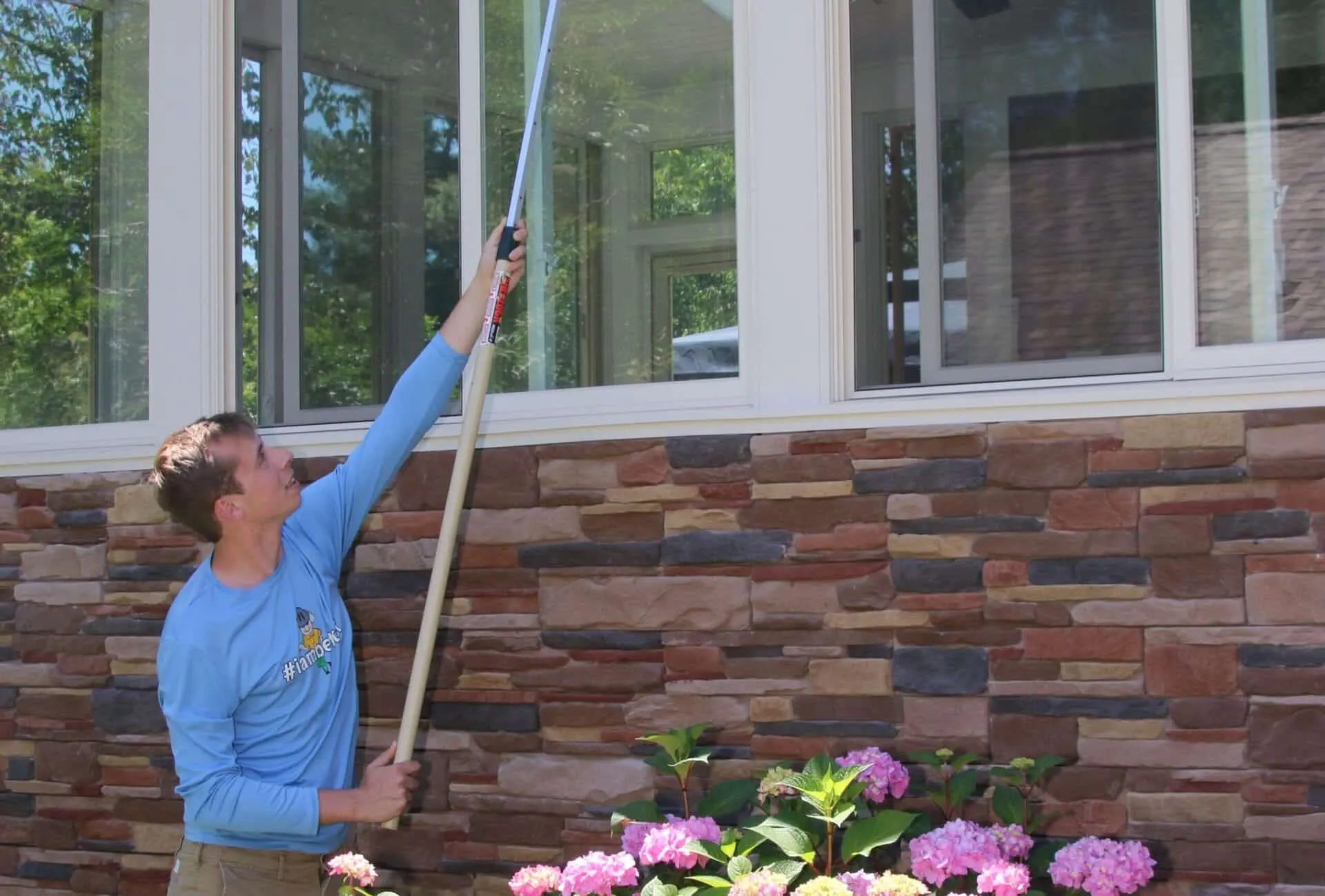 Better Termite technician dewebbing a porch with pink flowers in the foreground at a Northern Virginia home